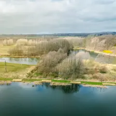 Krajobraz z jeziorami i lasem, gdzie widać ślady komercji w postaci przygotowanych miejsc nad wodą.