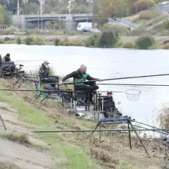 Wędkarze siedzą nad rzeką, łowiąc ryby.