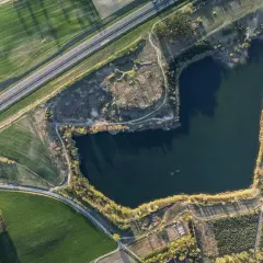 Widok z lotu ptaka na jezioro otoczone polami i drogą.