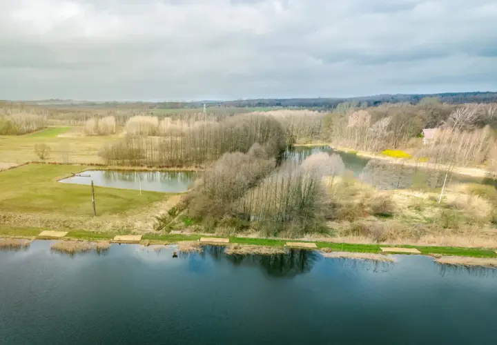 Krajobraz z jeziorami i lasem, gdzie widać ślady komercji w postaci przygotowanych miejsc nad wodą.