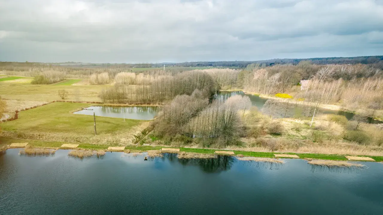 Krajobraz z jeziorami i lasem, gdzie widać ślady komercji w postaci przygotowanych miejsc nad wodą.