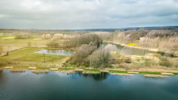 Krajobraz z jeziorami i lasem, gdzie widać ślady komercji w postaci przygotowanych miejsc nad wodą.